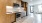 Model kitchen at our apartments in Richmond, featuring stainless steel appliances and wood grain floor paneling.